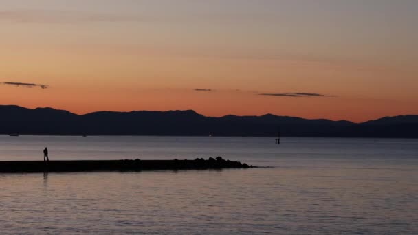 日出时分在海上的码头上行走的人 — 图库视频影像