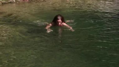 Alp gibi temiz su gölünde yüzen yetişkin bir kadın.