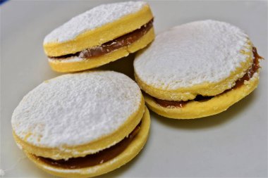 Alfajores: sweet cookies filled with milk caramel or  dulce de leche, dusted with powdered sugar. Soft and tempting, with an irresistibly appetizing appearance.  clipart