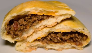  Beyaz bir tabakta lezzetli bir böreğin yakın çekimi. Altın-kahverengi, pul pul, sulu, iyi baharatlı et ve sebze dolgusunu ortaya çıkarmak için açılır. Taze pişmiş mükemmellik.!