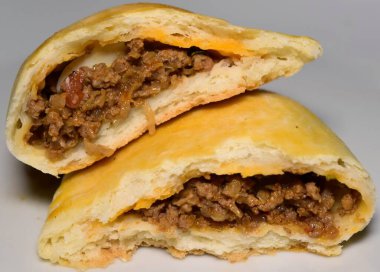  Beyaz bir tabakta lezzetli bir böreğin yakın çekimi. Altın-kahverengi, pul pul, sulu, iyi baharatlı et ve sebze dolgusunu ortaya çıkarmak için açılır. Taze pişmiş mükemmellik.!