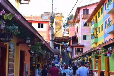 Canlı Guatap: renkli binalar, turistlerle dolu hareketli caddeler ve şenlikli bir atmosfer. Bayraklar gökyüzünü süslüyor, açık havada canlı bir sahne yaratıyor.. 