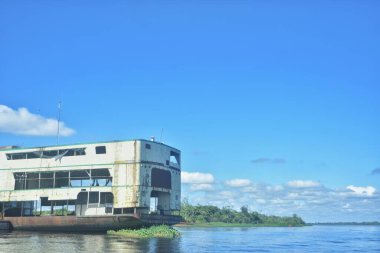 Iquitos 'taki Amazon Nehri' ne demir atmış büyük bir tekne. Pencereler seviyelerini süslüyor. Sakin sular, berrak gökyüzünü ve yemyeşil ağaçları yansıtır. Peru 'da huzur verici bir manzara yaratır.