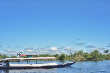 Iquitos 'taki Amazon Nehri' ne demir atmış büyük bir tekne. Pencereler seviyelerini süslüyor. Sakin sular, berrak gökyüzünü ve yemyeşil ağaçları yansıtır. Peru 'da huzur verici bir manzara yaratır.