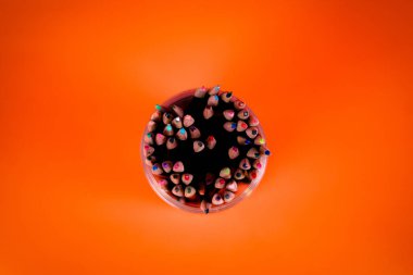 Turuncu arka planı olan renkli kalemler.