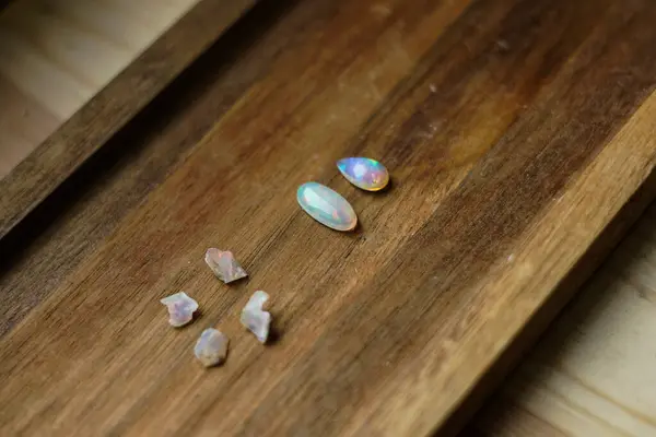 Rough and cut opal stones on the wooden background.