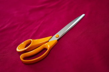 Mor tekstil üzerinde turuncu makas. 