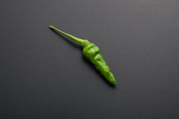 Fresh green chili pepper on black background