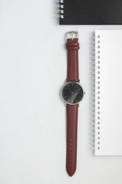 Beyaz ofis masasında kahverengi deri kayışla izle.