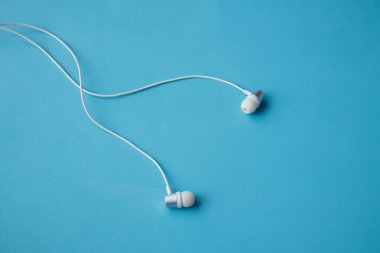 Mavi arka planda beyaz kulaklıklar. düz yatış, minimalizm.