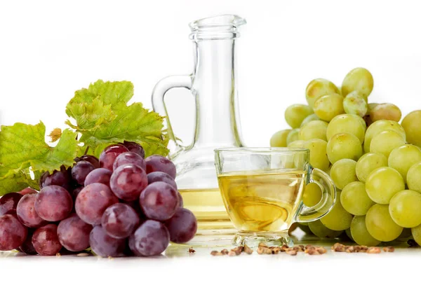 Grape seed oil on white background. The image also shows light grapes and dark grapes arranged on a white background