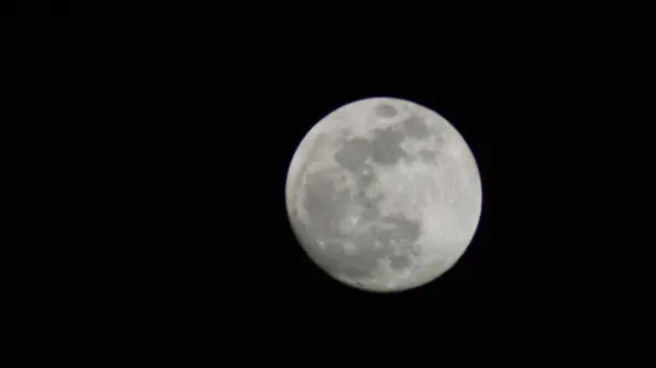 Dolunay, uzayın enginliğiyle çevrili görünür kraterlerle karanlık gece gökyüzünde parıldıyor.