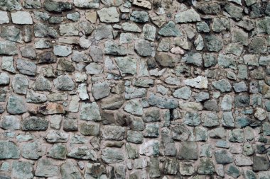 Doğal taş duvar kısmen yeşil bitkilerle kaplı. Arjantin, Bariloche, Rio Negro