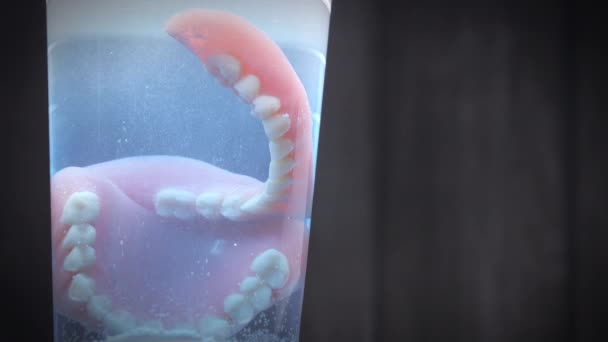 Temizlik Sıvısı Dolu Bir Bardakla Temizlenmiş Takma Dişlerin Yakın Çekimi — Stok video