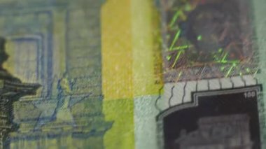 Closeup shot of a 100 euro paper money. Showing small details of the cash. Colors. European currency. Camera moving around.