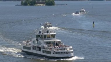 Helsinki.Finland-June 16.2021: Awesome shot of ferries traveling between Helsinki and the coastal islands. Amazing nature and beautiful sea on a sunny day. Tourist trips. Camera zooming out.