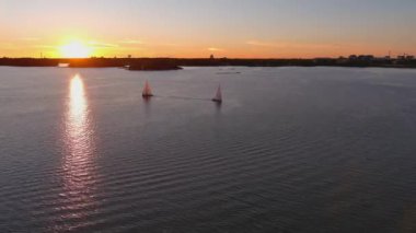 Finlandiya kıyı şeridi ve küçük adaların insansız hava aracı görüntüleri. Güzel gün batımı. Muhteşem İskandinav doğası. Küçük yelkenliler. Kamera yavaşça geriye hareket ediyor.