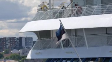 Tallinn.Estonya-21 Temmuz 2021: Bir yolcu gemisinde Estonya bayrağının güzel görüntüsü. Tallinn Limanı. Turizm. Arka planda bulutlu bir gökyüzü. Kamera yavaşça uzaklaşıyor.