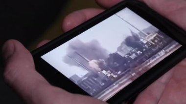 Ukrayna bombalama videosunu akıllı telefonundan izleyen birinin yakın çekimi. Askeri faaliyetler. Rus istilası Ukrayna kavramı. Bilgi savaşı. Arka plan bulanık. Seçici odak.