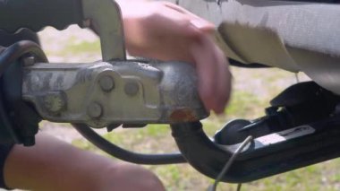 Metal kabloyu römorkun arkasına elleri kullanarak bağlamak. Karavanın çekici araca güvenli bağlantısı sağlandı. Yakın çekim görünümü.