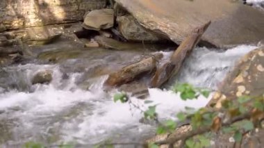 Norveç 'teki nehirde büyük kayalar ve kütükler şelale ve araziden akan sular. Yılın yaz zamanı. Alt kamera hareketi. Jeoloji görüntüsü.