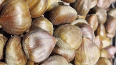Mağazadaki yenilebilir kestanelerin yakın çekimi. Yiyecekler. Zarif. Koyu ve açık kahverengi. Kamera yavaşça dönüyor. Dikey Biçim Videosu. 9:16 