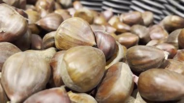 Süpermarket sepetindeki yenilebilir kestanelerin yakın çekimi. Koyu ve açık kahverengi. Yiyecekler. Seçici odak Kamerası yavaşça geriye doğru hareket ediyor.