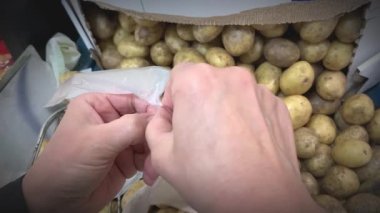 Arka planda patatesler olan bir süpermarkette plastik poşet açarken yakın çekim. Market alışverişi. Birinci şahıs vuruldu..