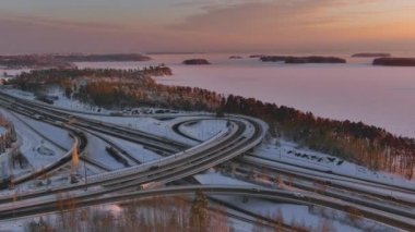 Espoo.Finland-3 Şubat 2022: Kışları Keilaranta 'da otoyolda araba kullanan araçların havadan çekimleri. Karlı şehir. Harika bir şehir manzarası. Donmuş deniz. İnsansız hava aracı geriye ve yana hareket ediyor.