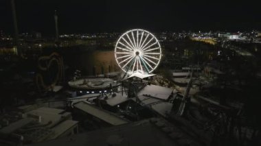 Helsinki. Finlandiya-18 Ocak 2022: Kış boyunca Linnanmaki 'de dönme dolabın yüksek açılı görüntüsü. Eğlence parkı. Gece vakti. Eğlence. İnsansız hava aracı yavaşça yana hareket ediyor.