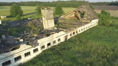 Paide, Estonya-5 Temmuz 2021: Harabe bir sığır ahırının havadan çekimi. Terk edilmiş Sovyet binası yavaş yavaş çürüyor ve doğayla bütünleşiyor. Drone yavaşça geriye doğru hareket ediyor.