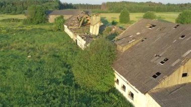 Paide, Estonia-July 5.2021: Aerial shot of a forgotten soviet cattle barn showing nature slowly taking over the old decaying structure.Nature taking over decaying structure.Camera moving over building