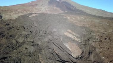 İspanya 'daki El Teide volkanının ucu gökyüzünde ve gökyüzünde görüldüğü gibi. Volkanik manzara. Kamera yavaşça yukarı doğru hareket ediyor.