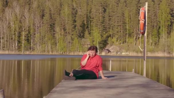 一位女士在漂浮的游泳桥上用电话交谈的搞笑镜头 芬兰迷人的自然与风景 相机慢慢放大 — 图库视频影像