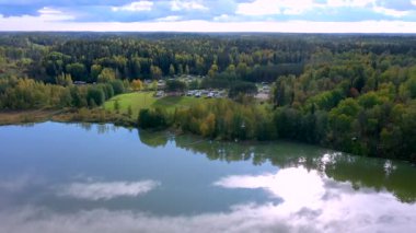 Finlandiya 'daki karavan bölgesinde gölün kenarındaki ağaçların hava manzarası