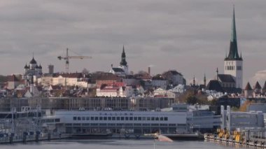 Tallinn.Estonya-14.2021: Yolcu gemisinden izlenen eski Tallinn şehrinin güzel görüntüleri. Kiliseler. Liman binası. Turizm. Bulutlu gökyüzü. Kamera yavaşça yana hareket ediyor.