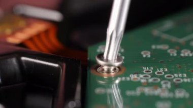 Sabit diski tamir ederken yakın çekim. Mikroçip. Tornavida. Farklı küçük parçalar. Depo. Bir vidayı çıkarıyorum. Bilgisayar teknolojisi onarılıyor. Seçici odaklanma. Kamera yavaşça yana hareket ediyor.