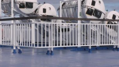 Tallinn.Estonya-14 Ekim 2021: Arka planda bulutlu gökyüzü olan bir yolcu gemisinde beyaz cankurtaran botları. Sakin deniz. Güvenlik. Beyaz korkuluk ve mavi zemin. Kamera yavaşça yukarı doğru eğiliyor.