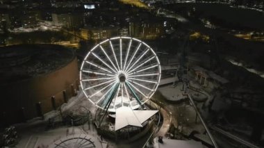 Helsinki. Finlandiya-18 Ocak 2022: Helsinki 'deki karlı Linnanmaki eğlence parkının yüksek açılı görüntüsü. Eğlence. Dönme dolap. Gece vakti. Kışın kapalıydı. İHA ilerliyor.