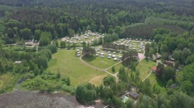 Göl kenarındaki bir karavan parkının güzel drone görüntüsü. Harika bir karavan yaşam tarzı ve mükemmel bir tatil fırsatı. Kamerayla çekilen hava jeolojisi yavaş yavaş ileri ve aşağı doğru hareket ediyor...