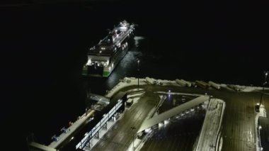 Helsinki. Finlandiya-18 Ocak 2022: Helsinki Finlandiya 'da Lansisatama' ya yanaşan bir geminin insansız hava aracı görüntüsü. Ulaşım. Kış zamanı. Batı limanı. Gece vakti. Kamera yavaşça geriye hareket ediyor.