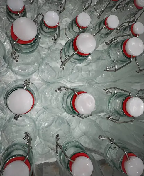 Parlak kırmızı lastik kaplamalı ve metal kaplamalı çeşitli cam şişeler, zarif şekillerini ve parlak yüzeylerini sergileyerek sanatsal bir görsel yaratıyor..