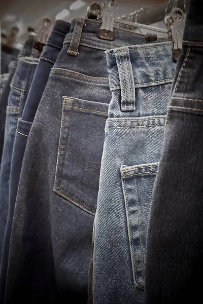 Askılarda farklı renkte kot pantolonlar sergileniyor ve sürdürülebilir ürünleri sergileniyor. Mağaza, atıkların geri dönüştürülmesi ve giysinin yeniden kullanılmasının önemini vurguluyor.