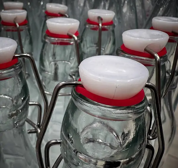 Kırmızı lastik mühürlü cam şişe koleksiyonu düzgünce sergileniyor. Şişeler içecekleri depolamak için tasarlandı ve özellikle bir markette sergileniyor..