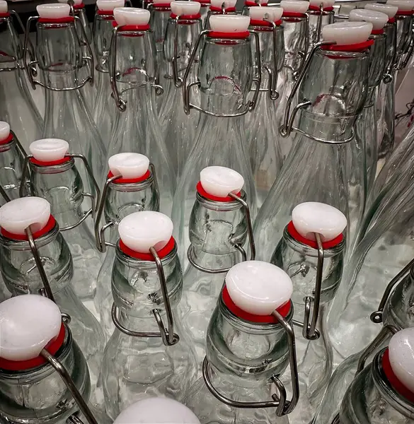 Kırmızı başlıklı temiz cam şişe koleksiyonu, zarif tasarımlarını ve ferahlık için fonksiyonel kilitleme mekanizmalarını gösteren bir masanın üzerinde yakından görüntülenir..