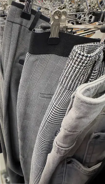 Çeşitli gri ve desenli pantolonlar ikinci el dükkanında raflara asılıp yeniden kullanım ve geri dönüşümü teşvik ediyor. Etkinlik, alışverişçiler için ikinci el giyim seçenekleri yoluyla sürdürülebilir modayı teşvik ediyor.