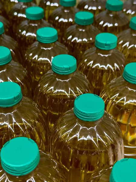 Renkli pişirme yağıyla dolu sıralar halinde temiz plastik şişeler market raflarında düzenli bir şekilde sergileniyor, parlak yeşil şapkaların altında alışverişçiler için canlı renklerini sergiliyorlar..