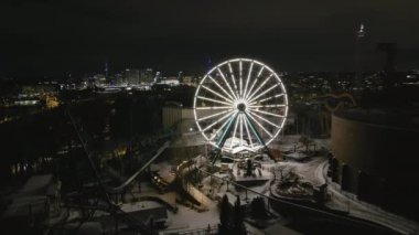 Helsinki. Finlandiya-18 Ocak 2022: Helsinki Finlandiya 'daki Linnanmaki eğlence parkının yüksek açılı görüntüsü. Dönme dolap. Kışın kapalıydı. Gece vakti. Eğlence. İnsansız hava aracı yavaşça ilerliyor.