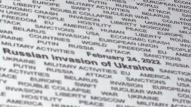 Rusya 'nın Ukrayna' yı işgaline yakın çekim. Beyaz kağıt üzerinde siyah metin. Kriz. Yaptırımlar. Askeri faaliyetler. Kamera hafifçe sola hareket ediyor. Seçici odak.