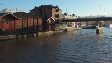 Porvoo.Finland-12 Aralık 2020: Porvoo Finland 'daki köprünün yanındaki nehir kenarındaki evlerin güneşli bir sonbahar gününün arka planında Finlandiya bayrağıyla daha yakın çekim 